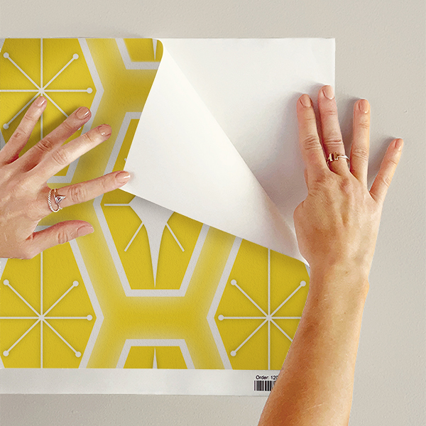 The artwork consists of a repeating geometric pattern featuring hexagonal shapes filled with two different designs. One design inside the hexagons includes a symmetrical starburst or asterisk-like figure with lines radiating from a central point, each line ending in a small circle. The other design features a white diamond shape with extended pointed ends within the yellow hexagon. These hexagons are outlined with a white border and set against a soft yellow background creating a vibrant, retro aesthetic. The use of yellow, white colors, along with the symmetrical arrangement, gives the pattern a mid-century modern, playful style.